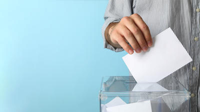 image d'une main déposant un buletin de vote dans une urne
